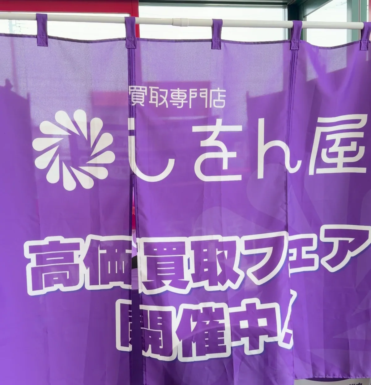 ブースを囲む紫の大きなのれん。「買取専門店 しをん屋」のロゴと「高価買取フェア 開催中!」の文字